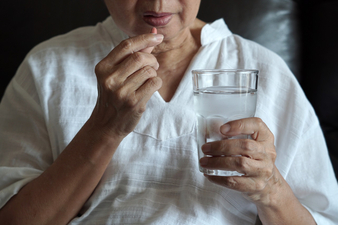 An old woman drinking vitamins