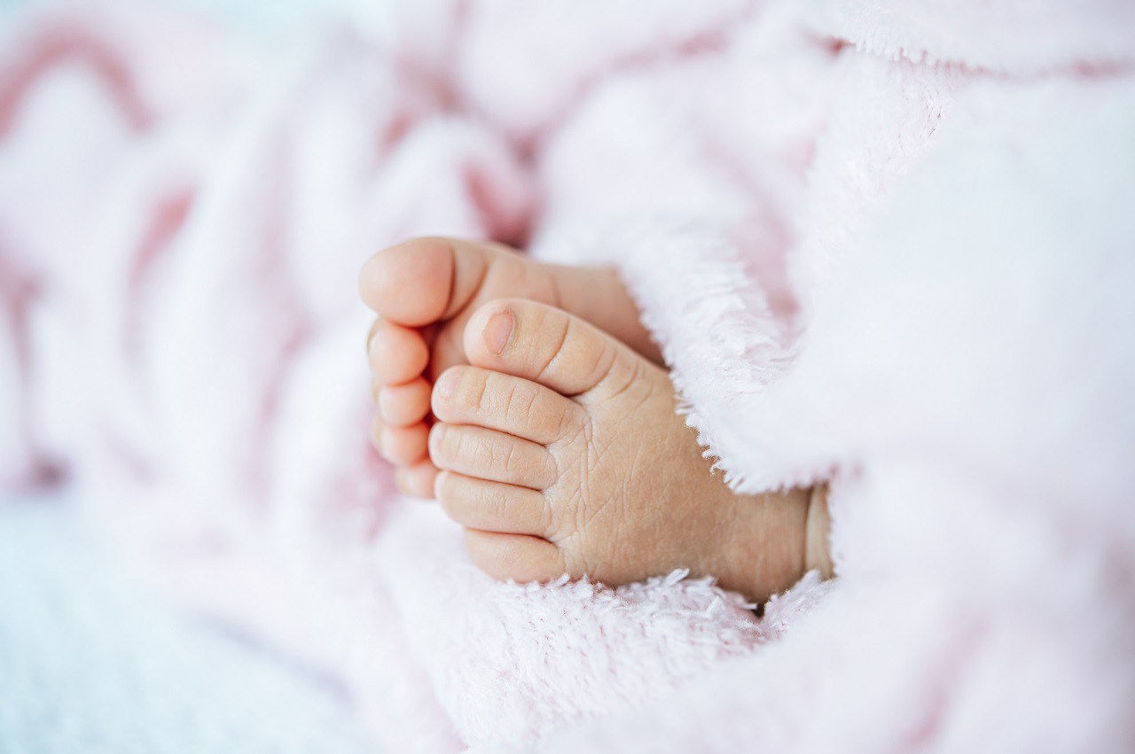 Close up of a newborn baby's feet wrapped in a white blanket