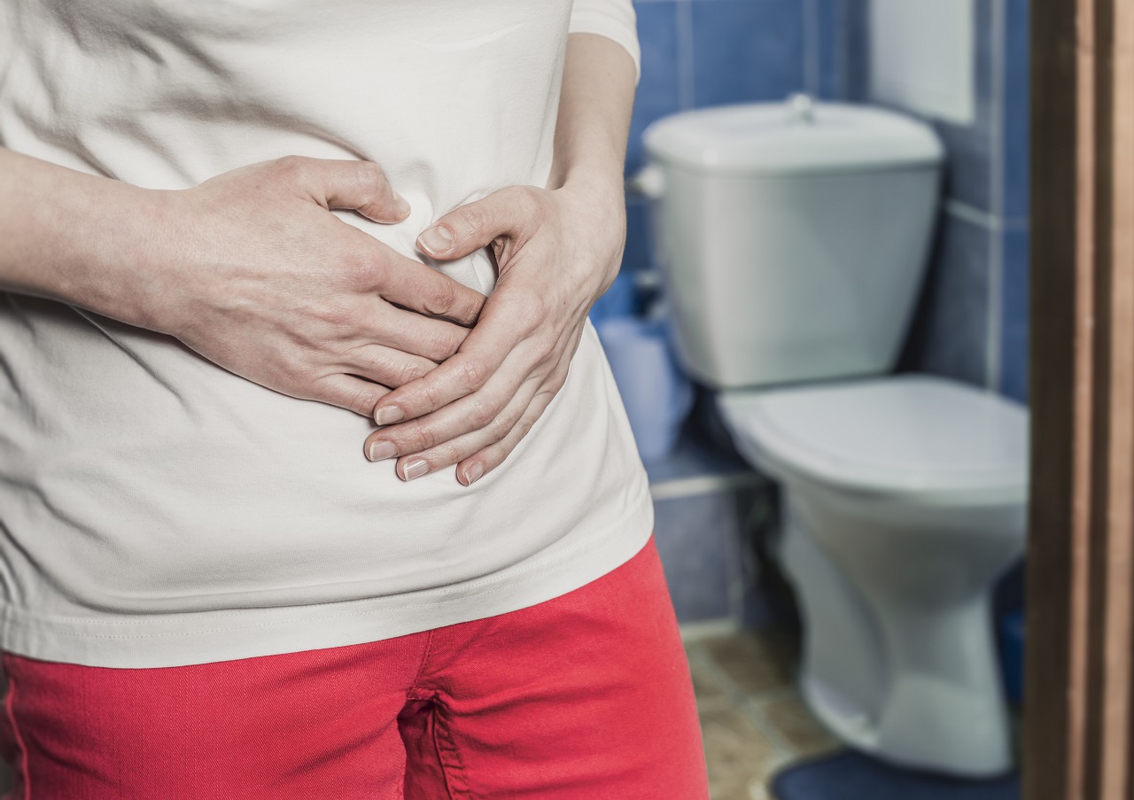 A woman clutching her stomach area in front of the bathroom