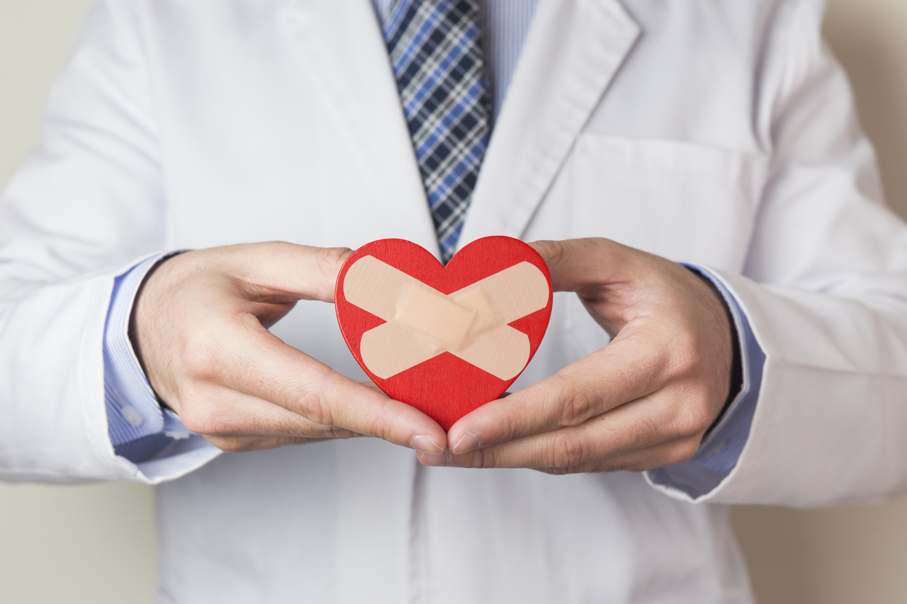 A doctor holding a heart with band aids