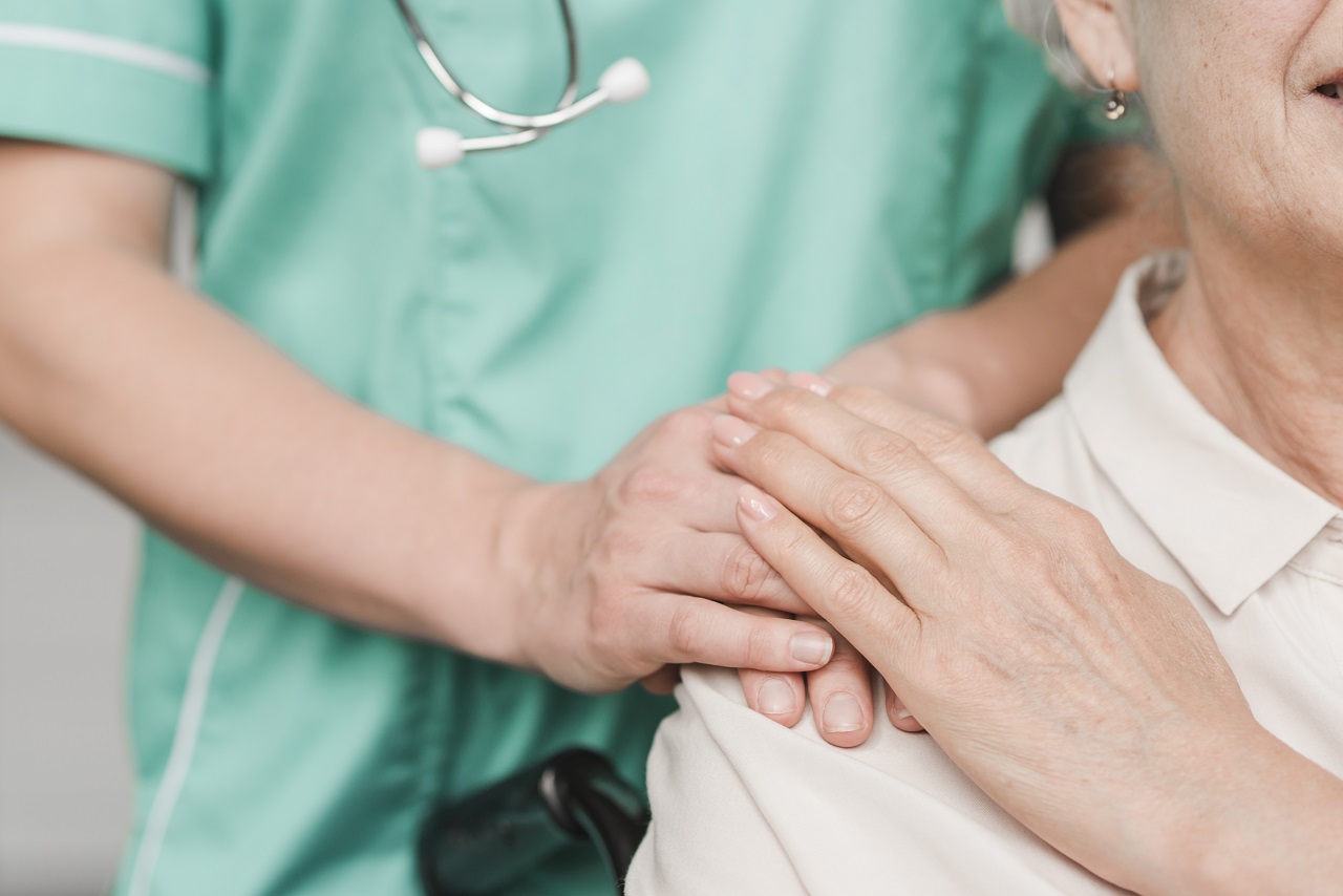 A male nurse helping an older woman patient