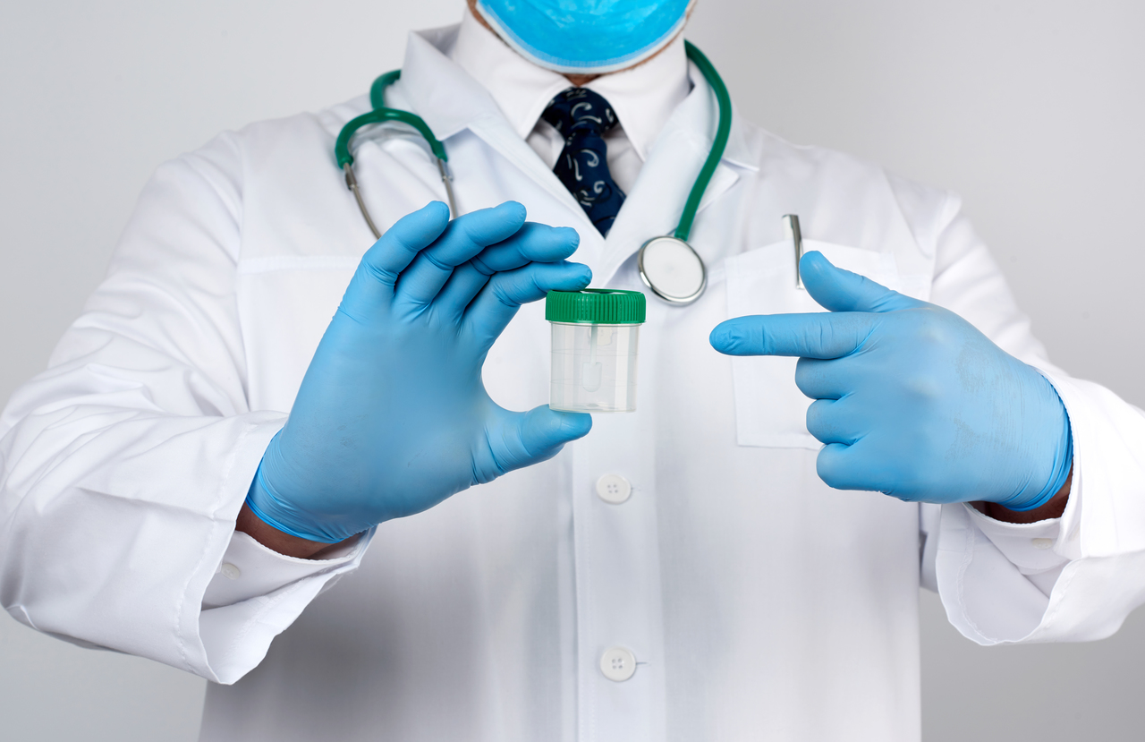 A doctor holding a jar for a stool sample