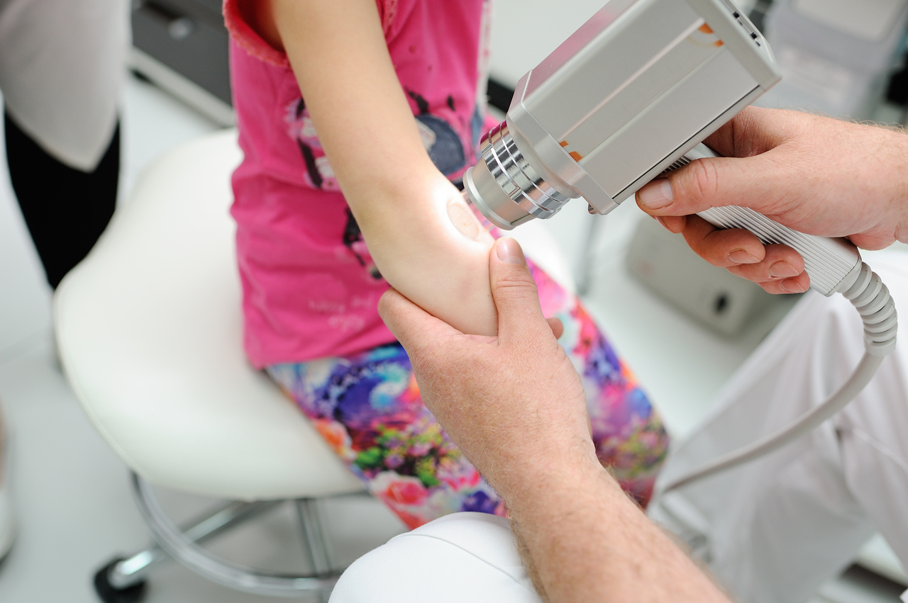 A doctor checking a child's arm for melanoma