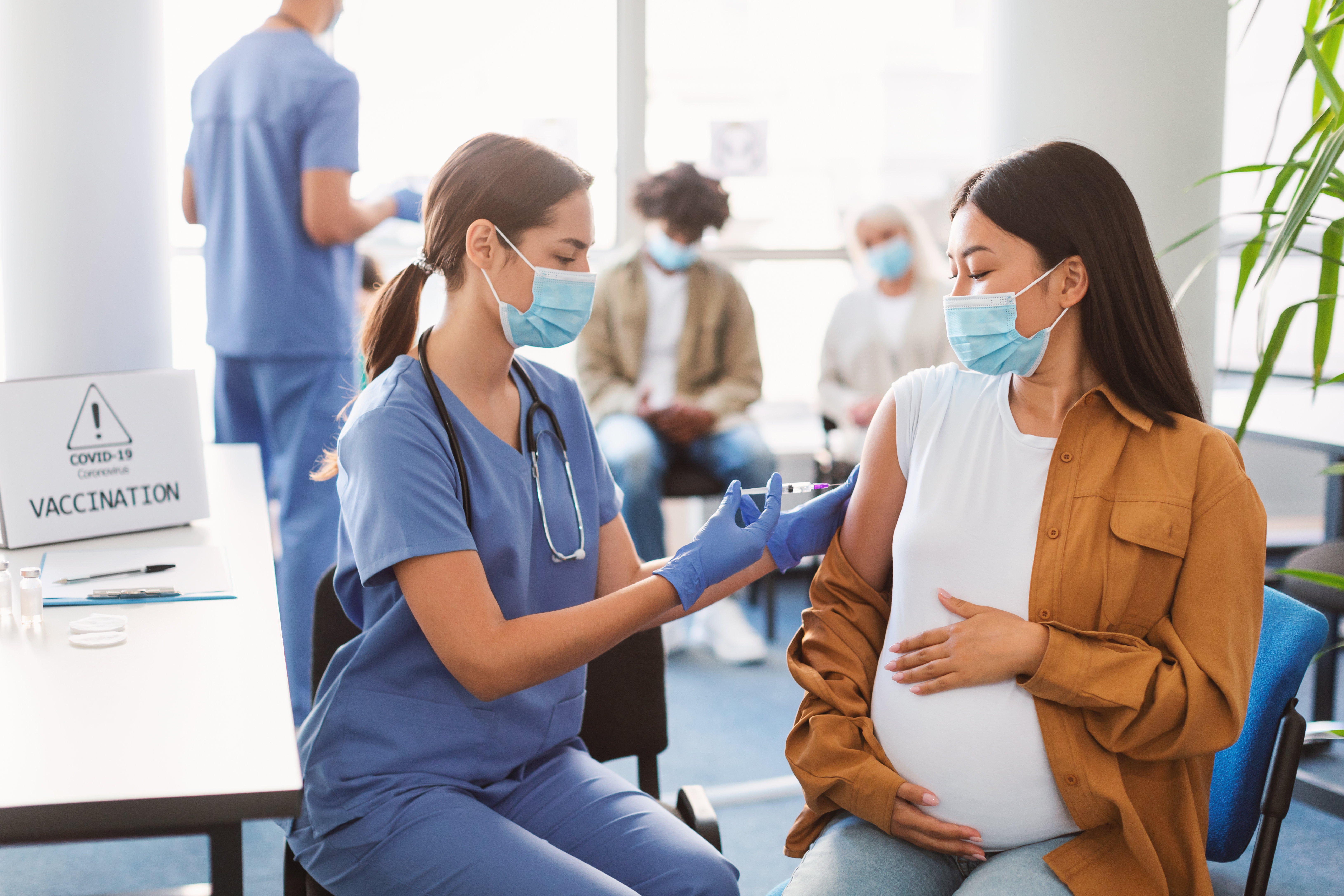Pregnant Asian Lady Receiving Vaccine Injection In Medical Centre